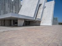 a white building with several steps and large glass panels in the facade is a mosaic that depicts a man