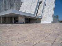 a white building with several steps and large glass panels in the facade is a mosaic that depicts a man