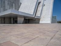 a white building with several steps and large glass panels in the facade is a mosaic that depicts a man