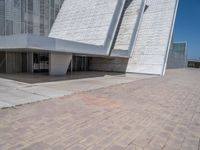 a white building with several steps and large glass panels in the facade is a mosaic that depicts a man