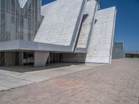 a white building with several steps and large glass panels in the facade is a mosaic that depicts a man