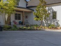 there is a house with a garage in the front of it and there are plants and trees growing on one side of the driveway