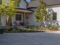 there is a house with a garage in the front of it and there are plants and trees growing on one side of the driveway