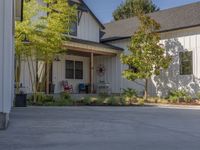 there is a house with a garage in the front of it and there are plants and trees growing on one side of the driveway