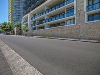 a street is lined with high rise buildings near an empty sidewalk with curbsides