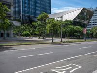 empty road with trees and a bus stop sign on it at an urban intersection in the city