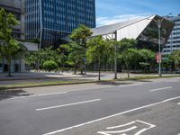 empty road with trees and a bus stop sign on it at an urban intersection in the city