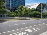 empty road with trees and a bus stop sign on it at an urban intersection in the city