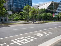 empty road with trees and a bus stop sign on it at an urban intersection in the city