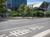 empty road with trees and a bus stop sign on it at an urban intersection in the city