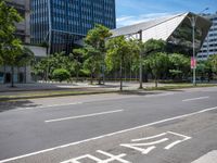 empty road with trees and a bus stop sign on it at an urban intersection in the city