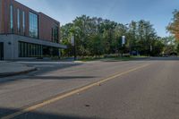 the empty road is lined with trees and buildings on either side of it in the summer