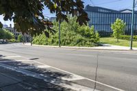 the sidewalk is empty on this city street by some tall buildings by the park area