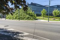 the sidewalk is empty on this city street by some tall buildings by the park area