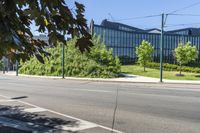 the sidewalk is empty on this city street by some tall buildings by the park area