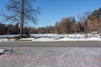 a snowy road with signs on the sides and trees in the distance with no leaves