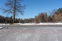 a snowy road with signs on the sides and trees in the distance with no leaves