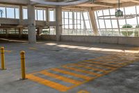 the empty area of an airplane hanger near many windows and a large circular metal object