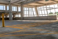 the empty area of an airplane hanger near many windows and a large circular metal object