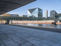 a skateboard sits outside a concrete structure that is next to a street area with a bench