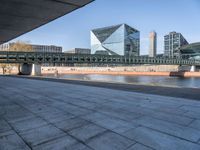 a skateboard sits outside a concrete structure that is next to a street area with a bench