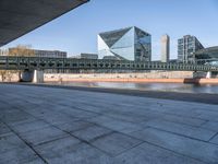 a skateboard sits outside a concrete structure that is next to a street area with a bench