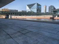 a skateboard sits outside a concrete structure that is next to a street area with a bench