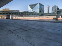 a skateboard sits outside a concrete structure that is next to a street area with a bench