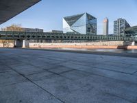 a skateboard sits outside a concrete structure that is next to a street area with a bench