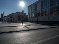 a street light next to an empty road in front of a building with a traffic light on top of it