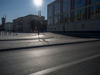 a street light next to an empty road in front of a building with a traffic light on top of it