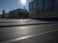 a street light next to an empty road in front of a building with a traffic light on top of it