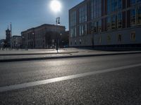 a street light next to an empty road in front of a building with a traffic light on top of it