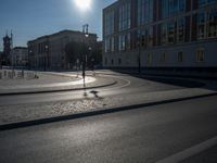 a street light next to an empty road in front of a building with a traffic light on top of it