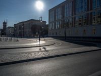 a street light next to an empty road in front of a building with a traffic light on top of it