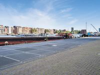 a large boat sits docked in a marina at the end of a street next to brick pavement