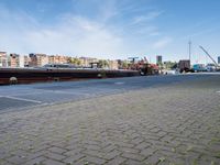 a large boat sits docked in a marina at the end of a street next to brick pavement