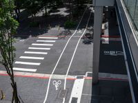 a street that looks straight ahead from a tall building with red stripes around it and bike symbols painted on the sidewalk