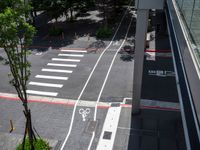 a street that looks straight ahead from a tall building with red stripes around it and bike symbols painted on the sidewalk