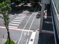 a street that looks straight ahead from a tall building with red stripes around it and bike symbols painted on the sidewalk