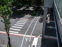 a street that looks straight ahead from a tall building with red stripes around it and bike symbols painted on the sidewalk