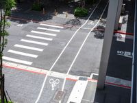 a street that looks straight ahead from a tall building with red stripes around it and bike symbols painted on the sidewalk