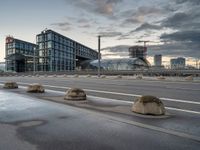 the buildings on the side of an urban road with cement boulders in front of them