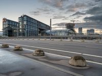 the buildings on the side of an urban road with cement boulders in front of them