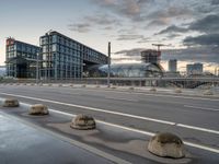 the buildings on the side of an urban road with cement boulders in front of them