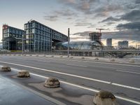 the buildings on the side of an urban road with cement boulders in front of them