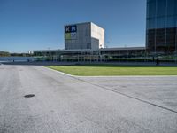 a man riding a bike past a tall building next to grass and parked cars,