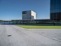 a man riding a bike past a tall building next to grass and parked cars,