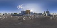 the sky is partly cloudy above a parking lot with arrows pointing down, and buildings near by