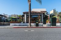 a small restaurant sits next to a street with palm trees and some benches next to it